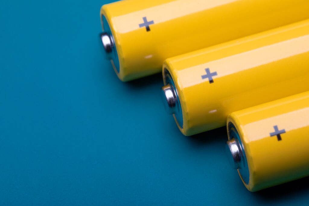 Close up shot of yellow AA alkaline or rechargeable NiMH batteries on blue background, shallow focus