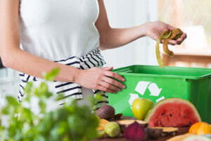 Experiment with Composting and Learn About Food Waste A person placing food scraps in a recycling container