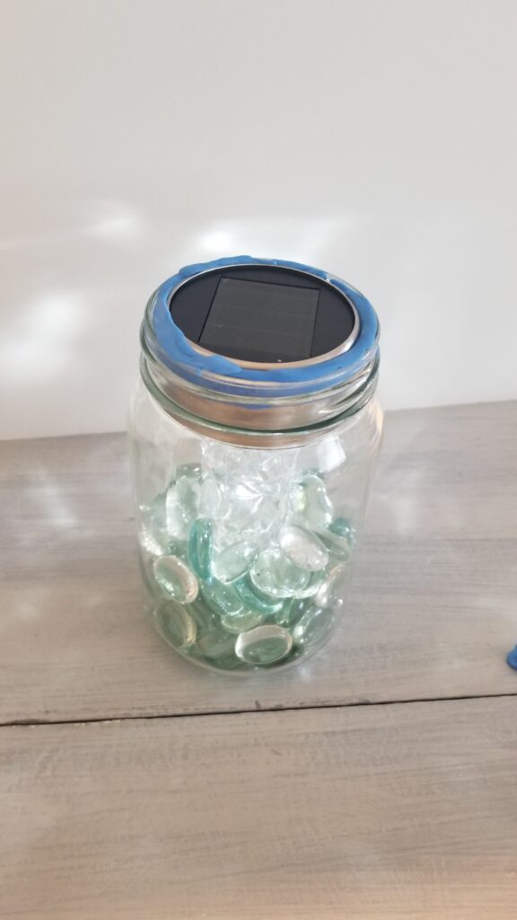 solar light with poster tack inside glass jar with acrylic beads