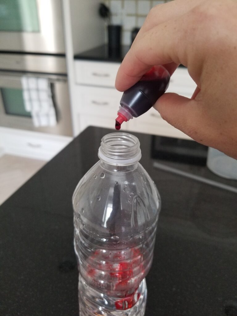 adding red food coloring drops to plastic bottle