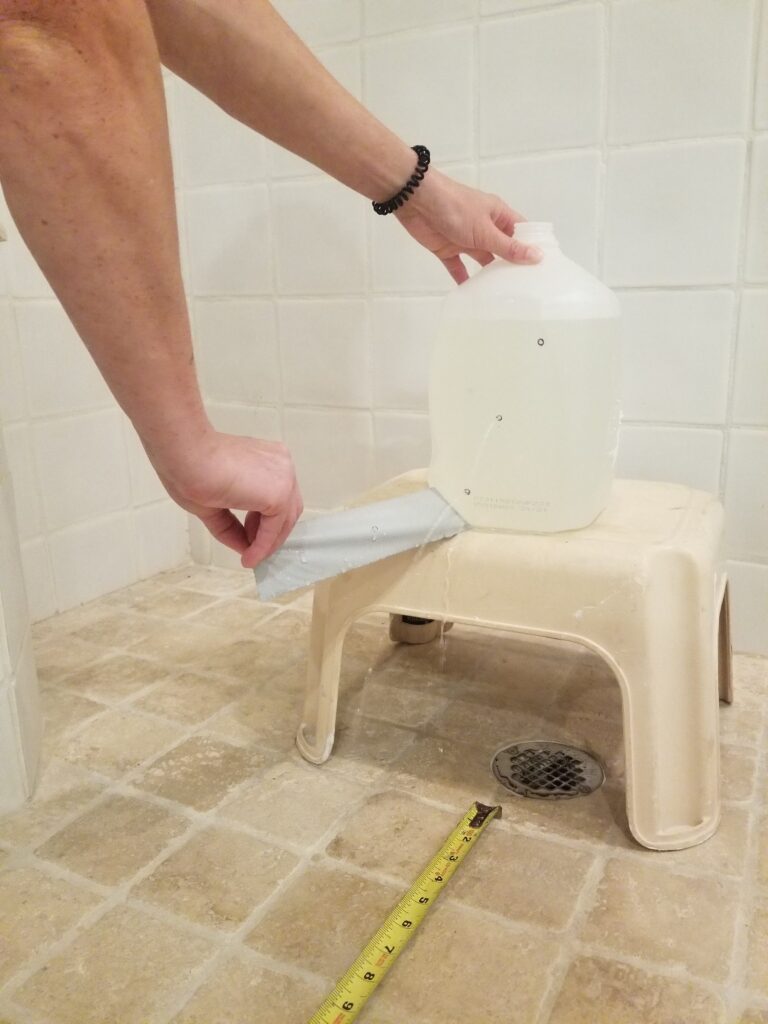 A person removing duct tape from a milk bottle to allow water to flow from it.