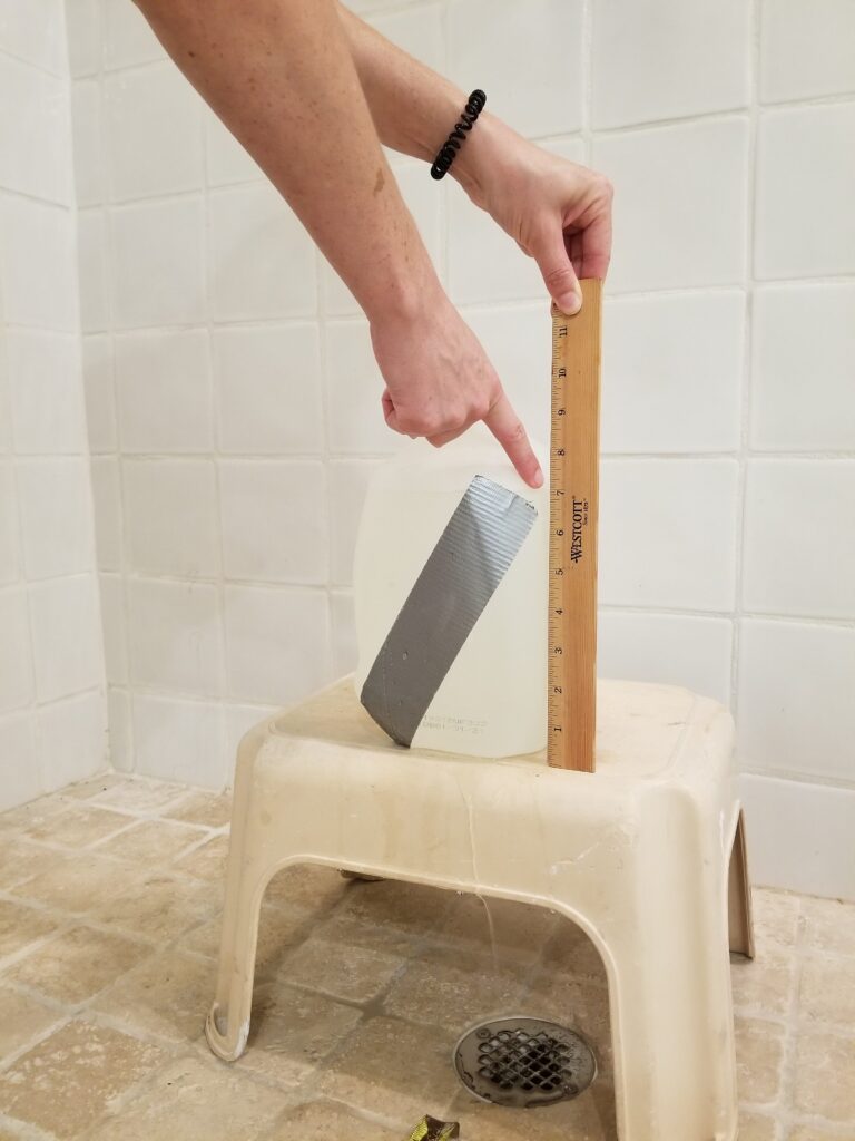 A person holds a ruler next to the milk jug to make measurements.
