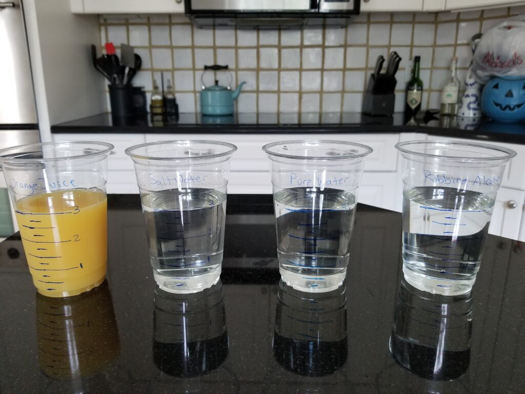 four plastic cups filled with different liquids
