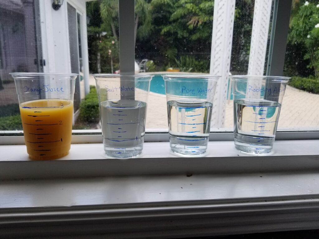 four plastic cups with different liquids sitting on a windowsill