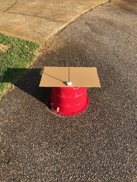 red plastic tub turned upside down with cardboard sundial on top