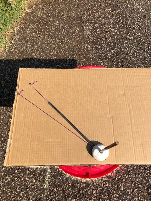 marking the time on the cardboard sundial at 9am