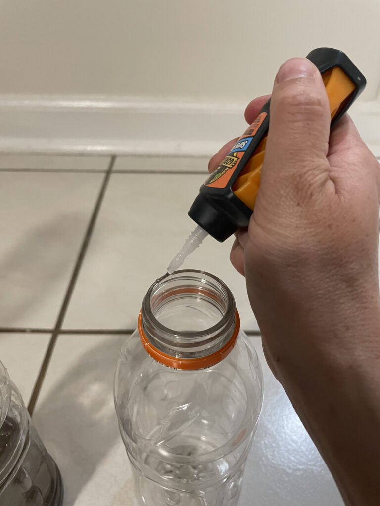 hand putting glue on top of plastic bottle lip