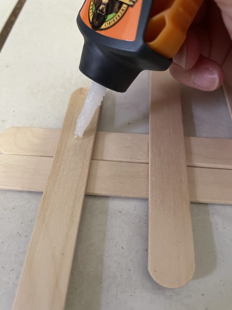 Glue being applied to a popsicle stick