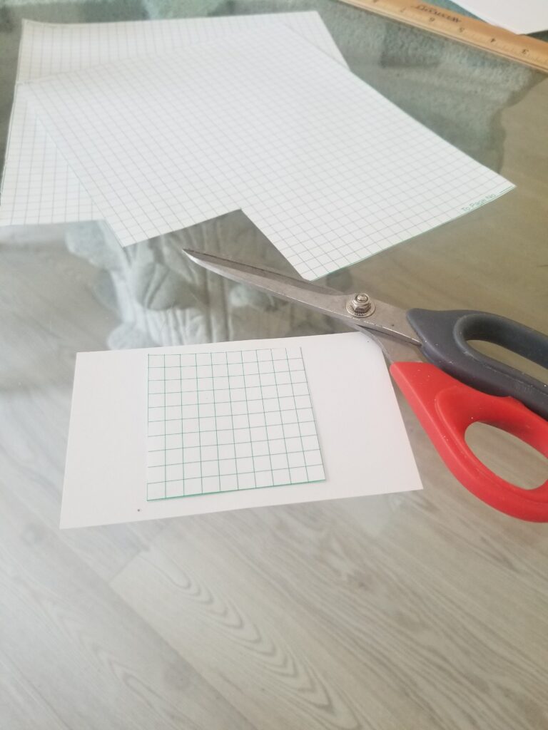 paper and square of grid paper next to scissors