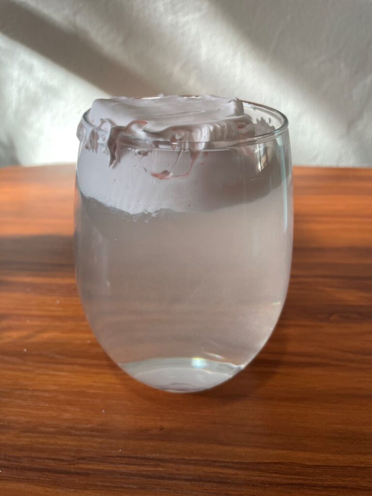 Glass of water with shaving cream on top of the water